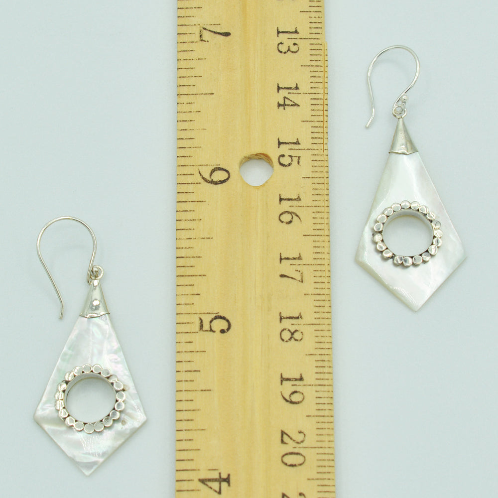 Abalone or Mother of Pearl Sterling Silver Earrings. Geometric diamond shape. Silver work. one and a quarter inch long. Pierced earrings. Fish hook There is a whole cut out in the center with silver scalloped around the edge of the whole.