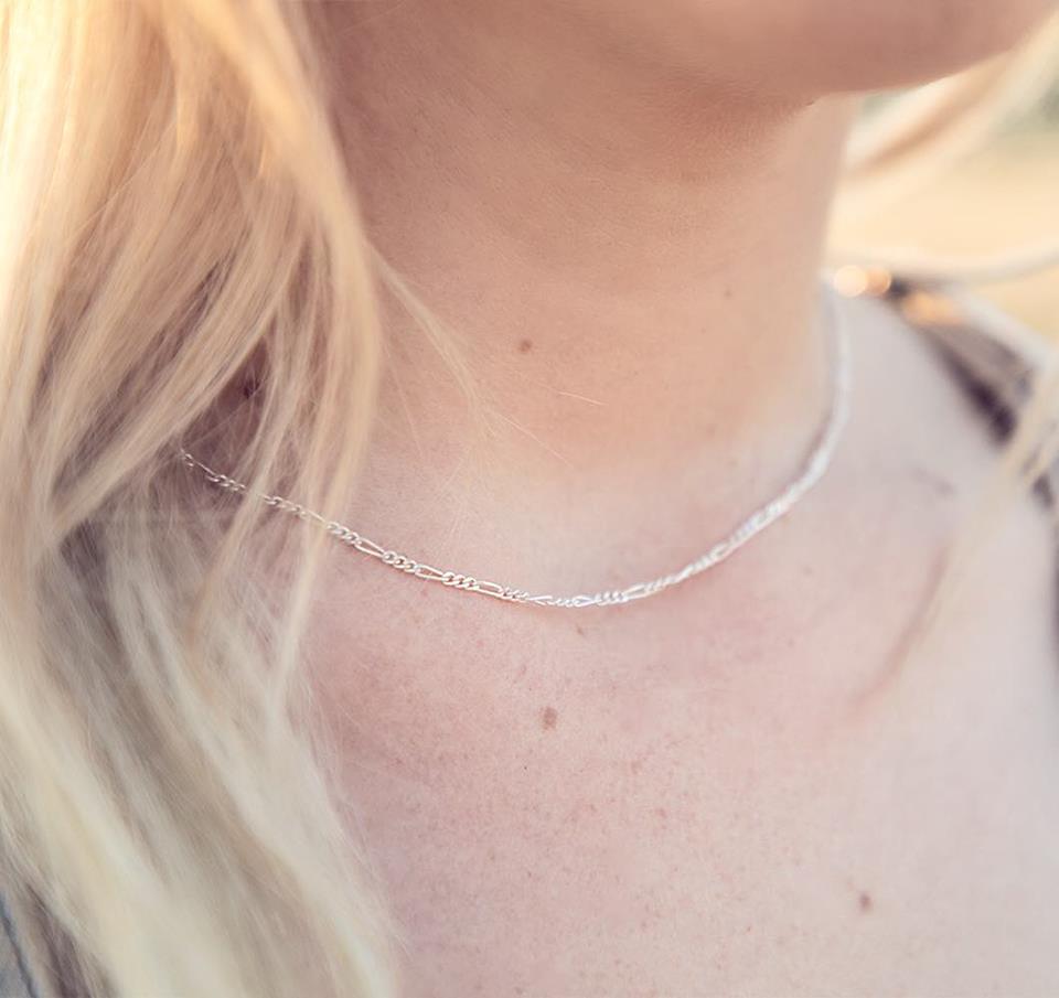 1.8MM Sterling Silver Figaro Chain For Men and Women. Perfect for pendants. Lobster claw clasp. Shown on a young woman who is very thin. 16".