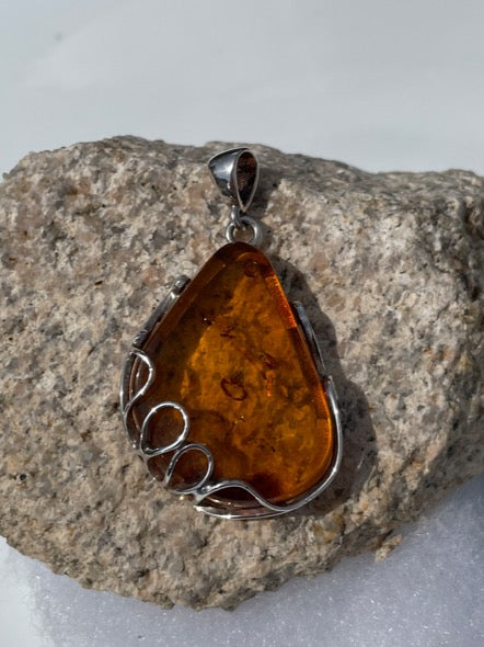 Amber sterling silver pendant. It hangs over an inch. It is a cognac color and the sterling silver that hugs the amber is in a beautiful design. truly for the amber lover.