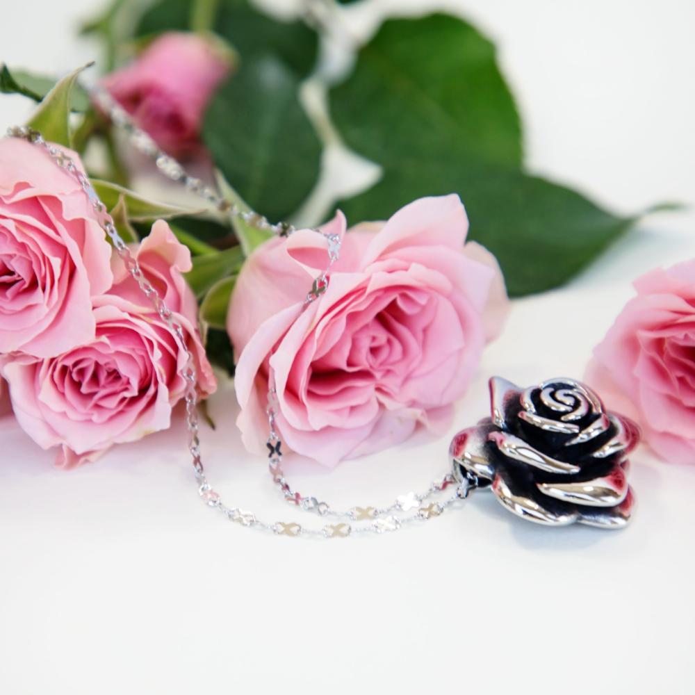 Large stainless steel rose pendant on our stainless steel infinity chain set by pink roses. This pendant will not tarnish or dent. Lovely rose flower pendant.